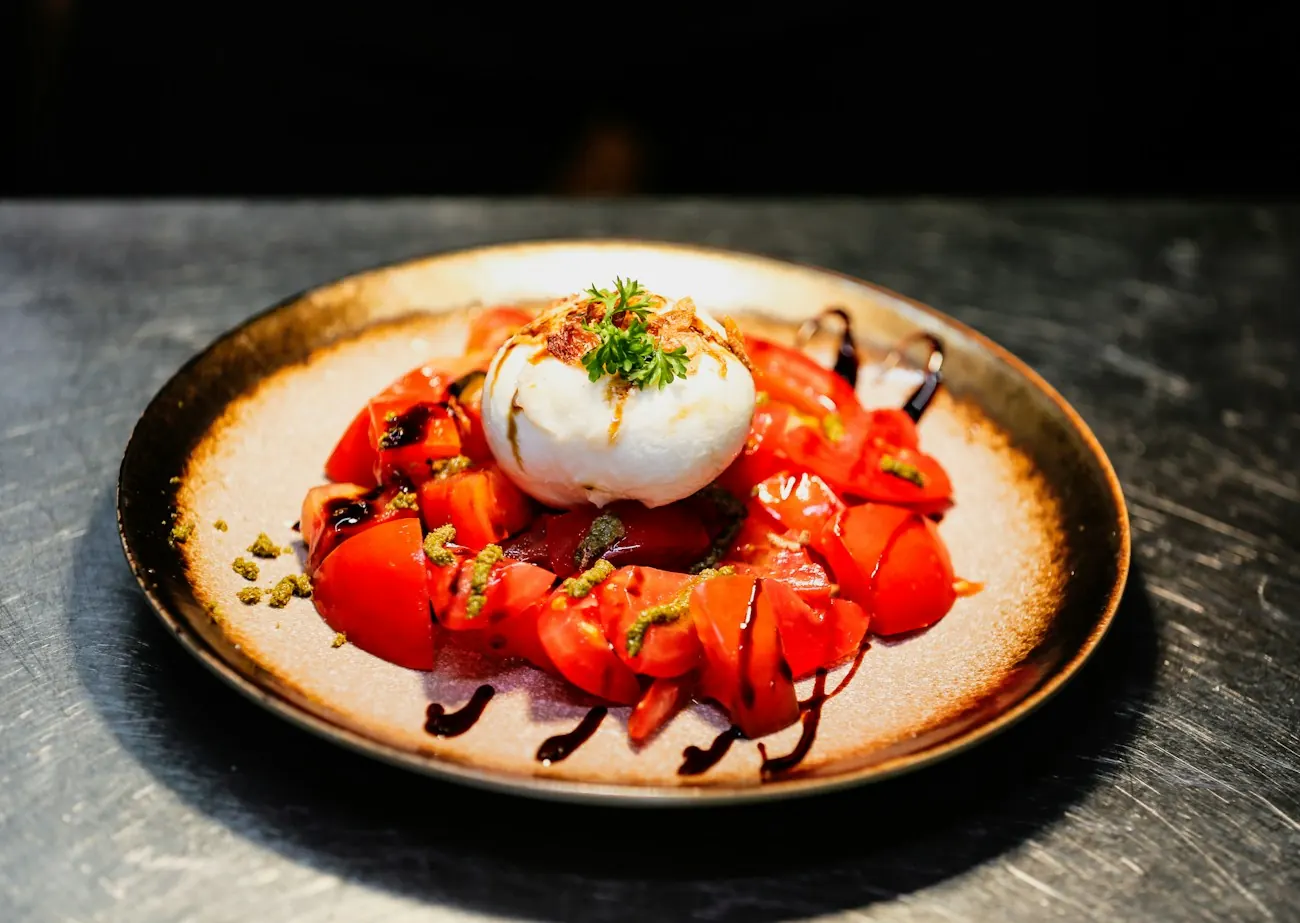 Burrata posée sur des tomates rouges, filet de vinaigre balsamique